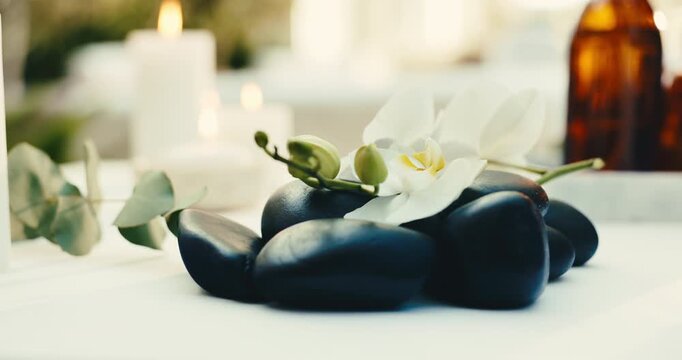 Flowers, stones and spa for relax, aromatherapy candle and natural wellness for stress relief. Basalt rocks, resort or orchids for therapy with calm, peace or holistic healing at luxury salon for zen