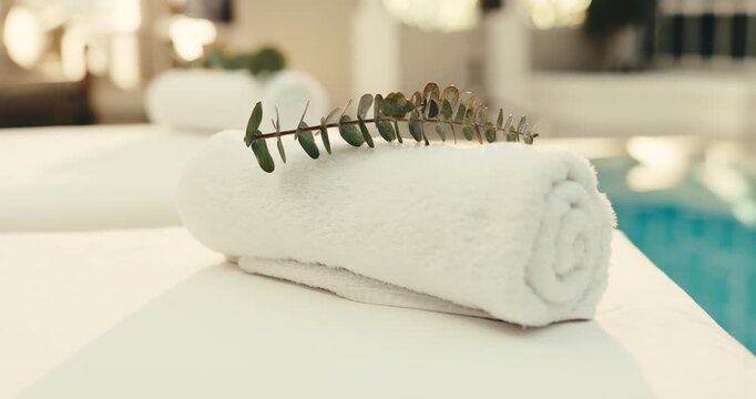 Towel, plant and spa with massage table in luxury resort for zen, accommodation or holiday getaway. Empty, leaves and fabric with cloth by poolside for hospitality, therapy or vacation in salon