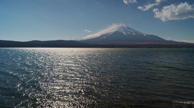 4K Scenic view of Mount Fuji covered with snow and lake in daytime under blue sky, Japan