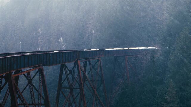 Old Rusty Train Trestle Bridge in Snowy Forest Landscape