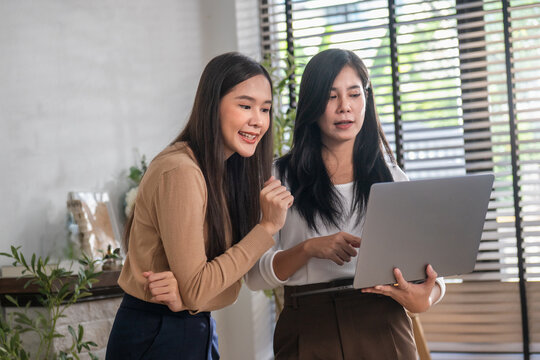 Two women collaborate warmly on a laptop