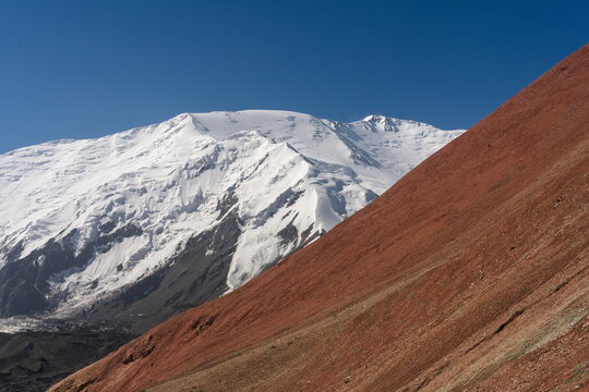 Lenin Peak's north face beside red slope of Travelers Pass, clear summer sky