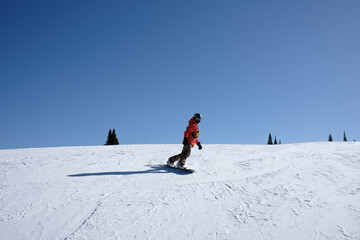 Snowboarder Carving Across a Snowy Slope Under Clear Blue Sky © Taras Vovchuk
