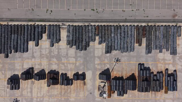 Aerial view of a metal construction company facility with organized rows of steel pipes in an outdoor yard, adjacent to an industrial building and solar panels in Milan, Lombardy, Italy