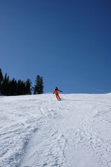 Skier in Orange Suit Descending Under a Deep Blue Winter Sky © Taras Vovchuk