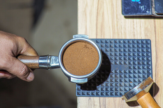 Hand holds coffee grounds in portafilter