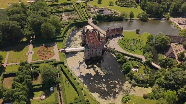 Aerial drone footage showcasing Egeskov Castle surrounded by landscaped gardens, ornamental lakes, winding paths, and lush green grounds in the Danish countryside.