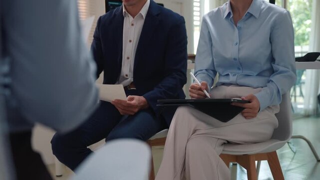 Group of business people discussing ideas and taking notes during a corporate training seminar in a modern office conference room