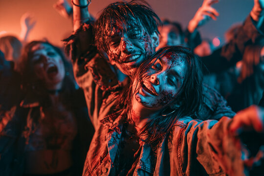 Zombie at Halloween Costume Party Featuring Bloody Undead Couple Dancing Together Among Energetic Costumed Horror Crowd
