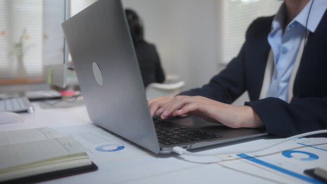 Call center agent hands typing on a laptop keyboard providing customer service support in a busy modern office environment