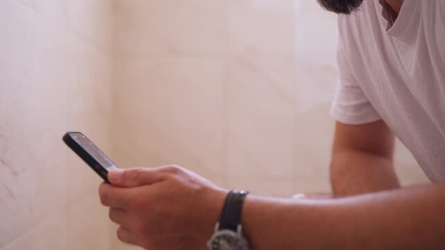 Adult man sitting on toilet using smartphone during a private moment, engaging in masturbation and self-stimulation, representing private adult behavior, digital habits and personal leisure.