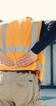 Worker, man and back pain on construction site with injury, building accident and massage for relief. Hurt, person and builder outdoor with muscle inflammation, fatigue and overworked from project.