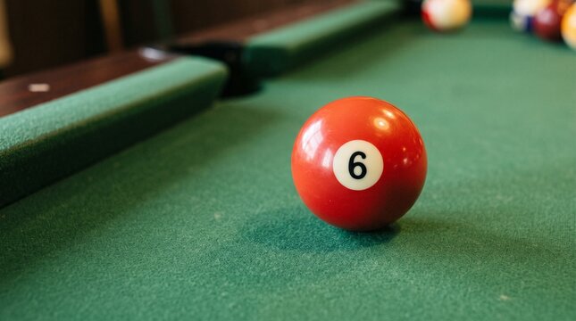 Red billiard ball number six close up on a green pool table