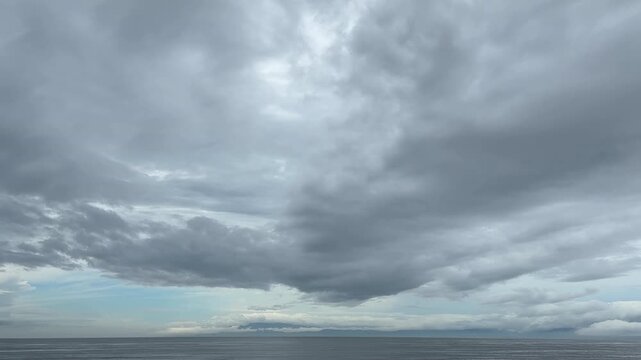 雲の隙間から柔らかな光が差し込む静かな海の景色
