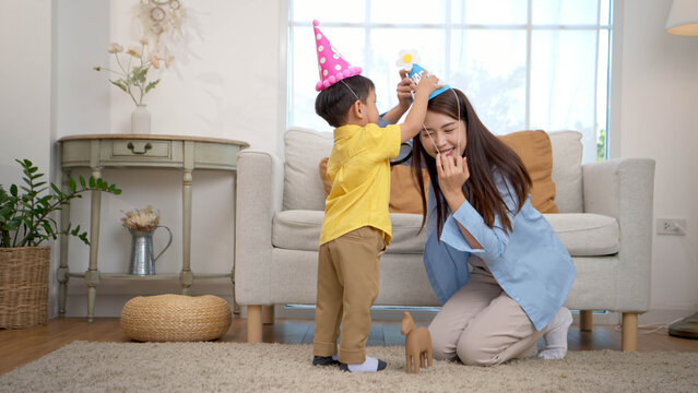 Mother placing a party hat on Little boy, showing warm bonding and social learning