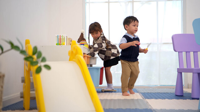 The girl helps the boy choose toys from the cupboard to play with together at the table
