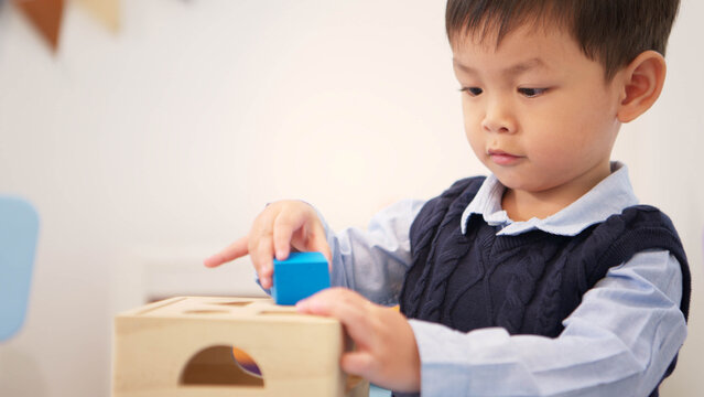 Little boy playing with educational toys on the table, improving learning and hand-eye coordination