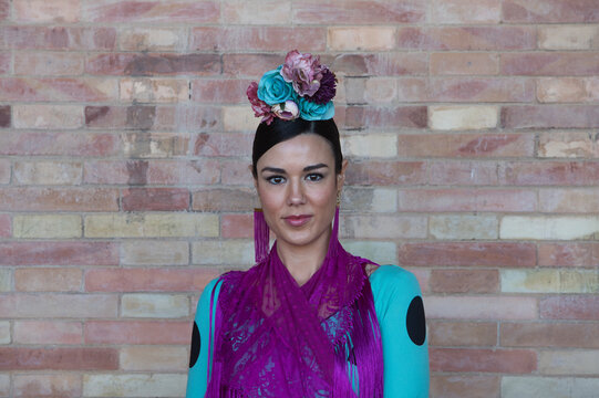 A beautiful woman dancing flamenco in a square in Seville, Spain. She is wearing a turquoise dress with black polka dots and a flower in her hair. Flamenco, a UNESCO Intangible Cultural Heritage.