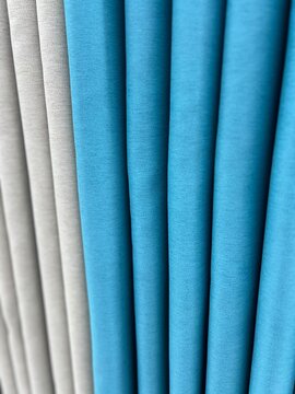 Elegant window curtain drapes featuring soft grey and bright blue fabric layers with smooth vertical folds and high quality textile material texture