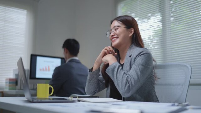Successful asian businesswoman celebrating good news using a laptop in a modern office at night