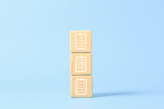 Stacked wooden blocks with checklist icons represent task management, planning, audit, quality control, project progress, organization, compliance, and completed work goals. concept.