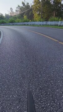 POV cycling footage approaching a sharp curve on a forest mountain road, featuring fresh asphalt, lush vegetation, roadside barriers and a peaceful outdoor landscape.