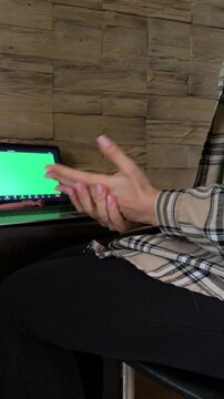 Woman wringing her hands and gesturing nervously at a laptop displaying a green screen while attending an online psychotherapy session for mental health support