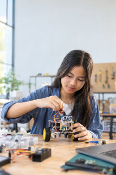 Southeast Asian teenage girl building an educational robot