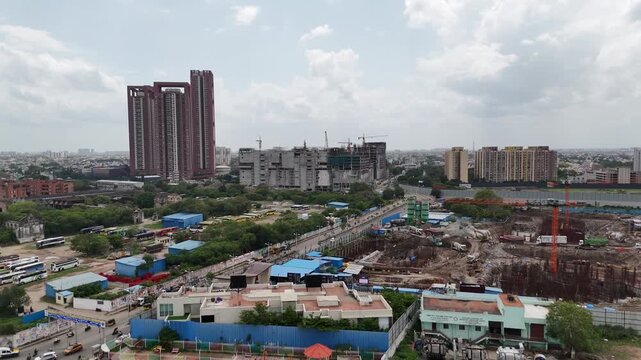 Cinematic aerial view of Chennai city showcasing a prominent cluster of tall high-rise residential towers rising above the urban skyline, surrounded by ongoing construction, apartment complexes, roads