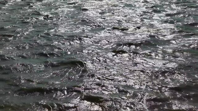 Sparkling river water surface flowing with sun glare reflections, abstract natural background, of rippling waves, and moving currents