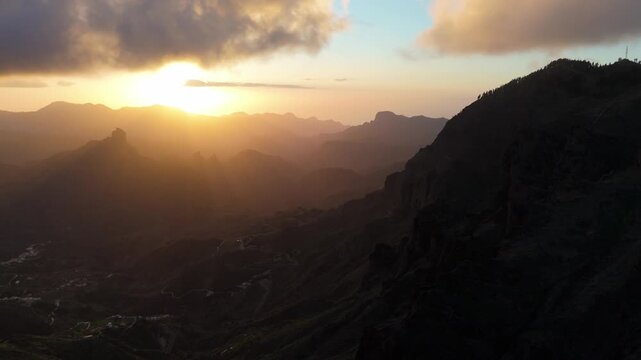 Drone booms up and pushes in over the stunning mountainous landscape of Gran Canaria at sunset. Capturing a remote, rugged valley and majestic peaks.