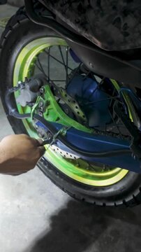 mechanic's hand using a wrench to work on the rear wheel assembly of a dirt bike. Concept for professional motorcycle brake repair and mechanical maintenance.