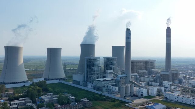 Large thermal power plant cooling towers and smokestacks emitting steam