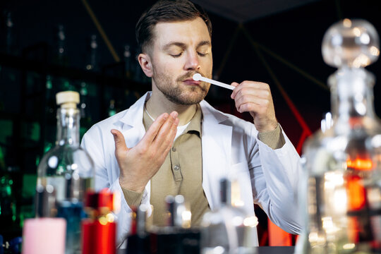Professional perfumer smelling a fragrance on a blotter strip, developing new aromas in a perfume laboratory