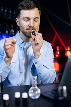 Young man creating and testing new fragrance formulations in a modern laboratory, choosing the best aroma for perfume