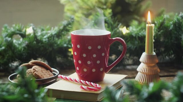 Mug of hot tea or coffee against background of Christmas interior. Cozy winter season.