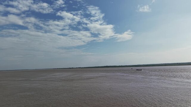 Wide river landscape with small fishing boat sailing under blue sky and clouds water nature
