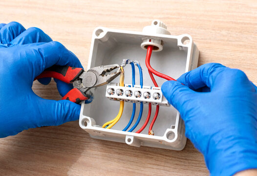 Electrician connecting wires inside a junction box with pliers