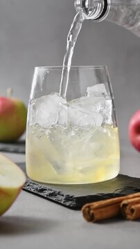 Tonic water pours over apple cider and ice during preparation of apple cider cold brew tonic drink.