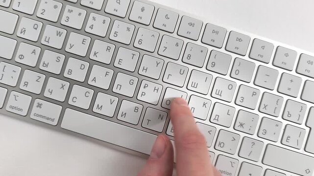 Slow typing on keyboard with a single finger carefully selecting letters on buttons. User enters a precise password or a beginner learns how to operate desktop technology. Top down view