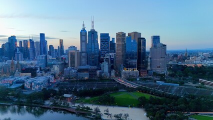 Fototapeta premium Melbourne, Victoria, Australia by night– 4K aerial drone view of Melbourne CBD skyline, Yarra River, Arts Centre, Flinders Street Station and illuminated skyscrapers at sunset twilight