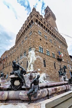View of the historic Palazzo Vecchio and the ornate Fountain of Neptune with its marble and bronze statues, Florence, Tuscany, Italy.
