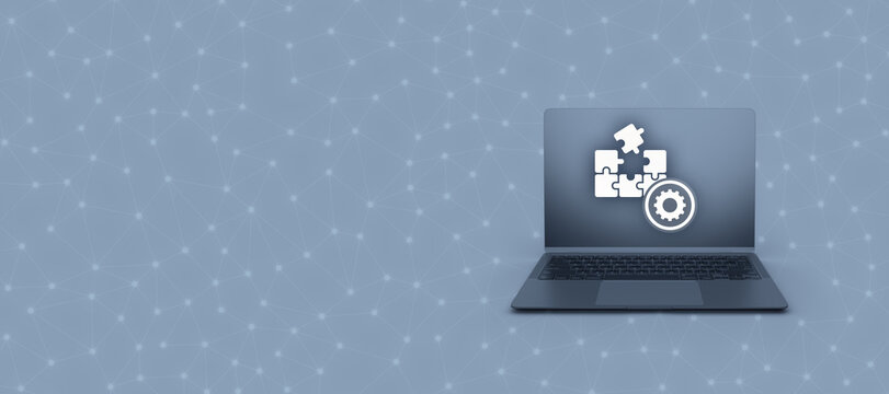 A dark laptop sits on a grey network background with a puzzle and gear icon on the screen, creating a modern digital concept with generous copy space.