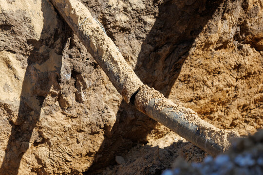 Weathered pipe embedded in rough, sunlit earth