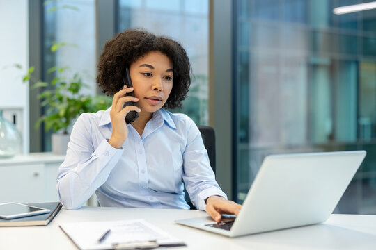 Business communication and remote work, professional woman talking on smartphone while working on laptop in modern office, Focused employee multitasking with digital technology and corporate