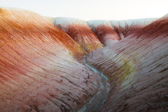 View of the striped clay formations of Kyzyl Kup, also known as Tiramisu, featuring eroded red and white layers in a dry canyon in Karakiya District, Mangystau Region, Kazakhstan.
