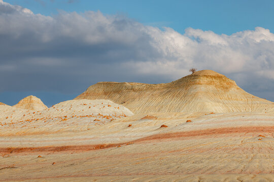 View of the layered sedimentary rock formations of Kyzyl Kup, also known as Tiramisu, in the desert landscape under a cloudy sky in Karakiya District, Mangystau Region, Kazakhstan.