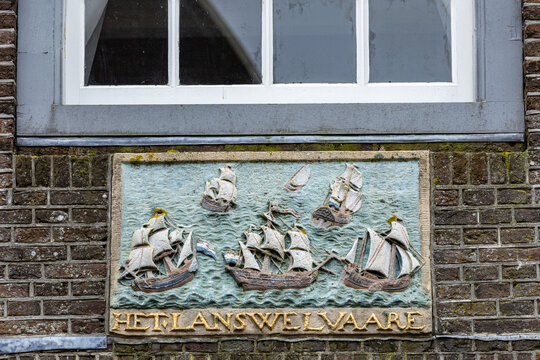 View of a historic stone relief depicting sailing ships on a brick wall in Monnickendam, North Holland, Netherlands.