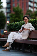 Obraz premium Woman using smartphone relaxing on park bench