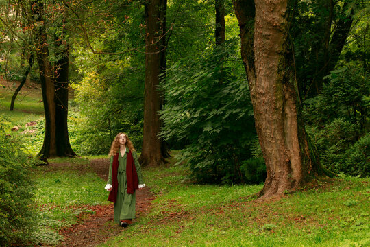 Woman in vintage green coat walks through a peaceful woodland path cottage core aesthetic moody lifestyle time